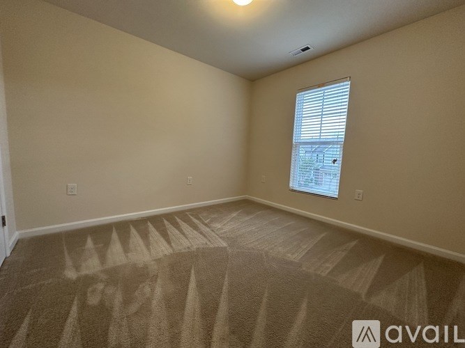 A room with a carpeted floor and a window with blinds.