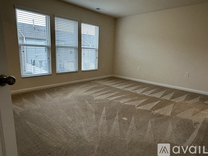 A room with a carpeted floor and a window with blinds.