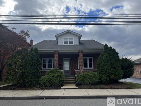 A house with a front yard and a sign that says "AVAIL".