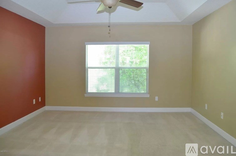 A room with a ceiling fan and a window with blinds.