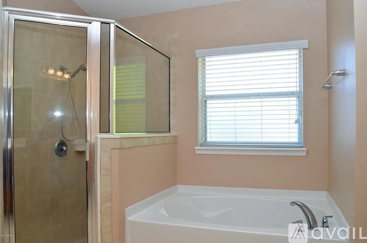 A bathroom with a white tub and a glass shower door.
