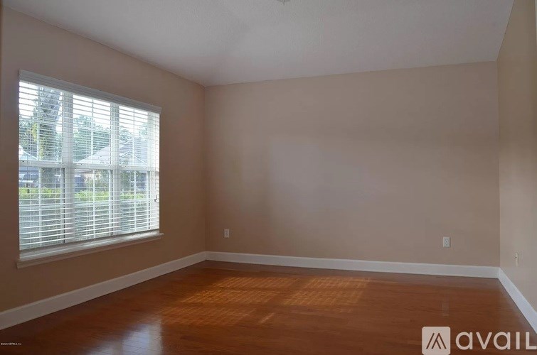 A room with wooden floors and a window with blinds.