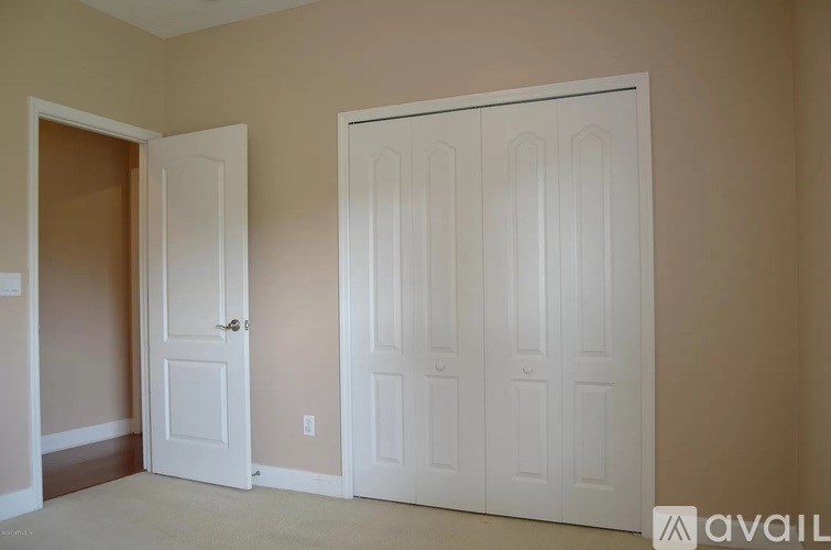 A room with two white doors and a beige wall.