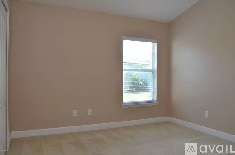 A room with beige walls and a window with blinds.