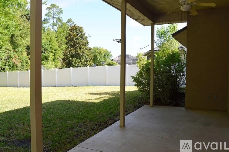 A porch with a view of a white fence and trees.