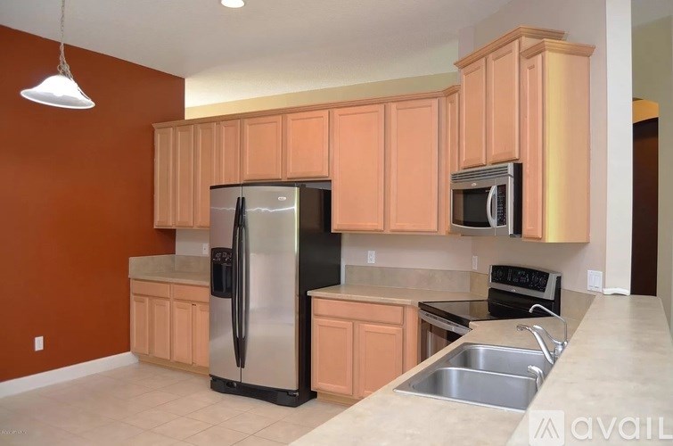 A kitchen with orange cabinets and a black refrigerator.
