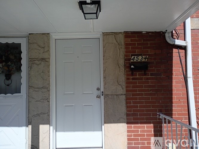 A white door is on the left of a brick wall with a number 453 on it.