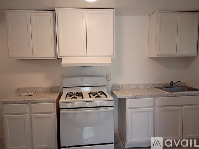 A kitchen with a white stove and cabinets.