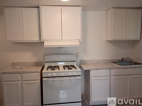 A kitchen with a white stove and cabinets.