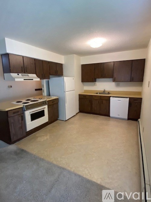 A kitchen with brown cabinets and white appliances.