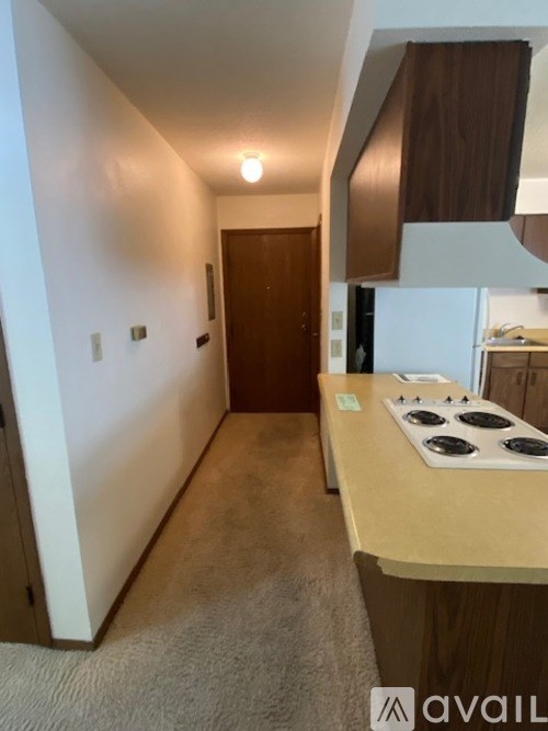 A kitchen with a stove top oven and a carpeted floor.