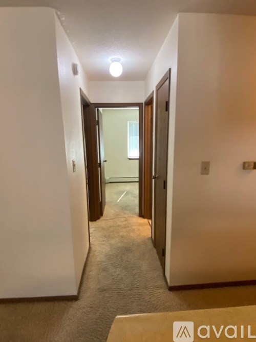 A hallway with a carpeted floor and white walls.