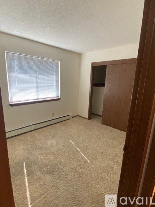 A room with a carpeted floor and a window with blinds.