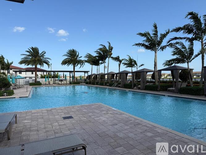 A pool surrounded by palm trees and lounge chairs.