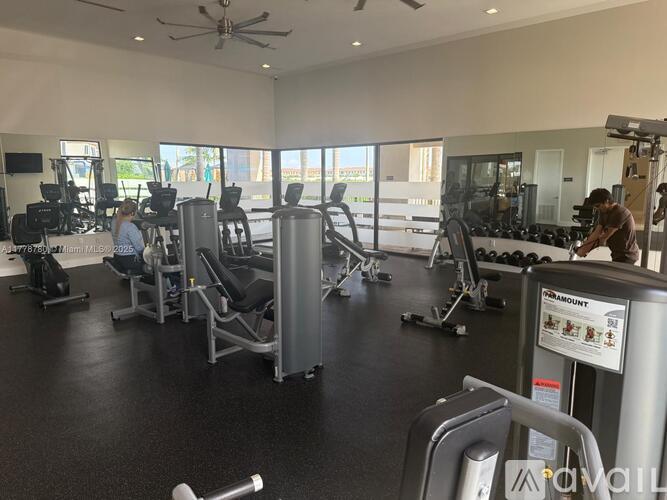 A gym with a variety of equipment and two people working out.