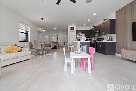 A modern living room with a white sofa and a dining table with pink chairs.