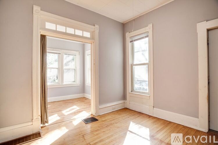 A room with a large mirror and two windows.