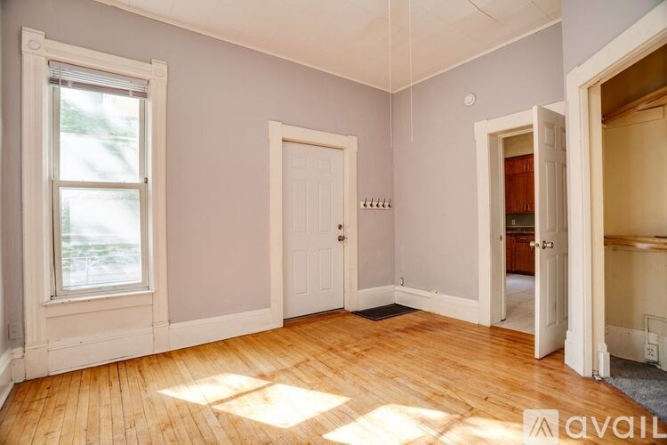 A room with wooden floors and a window letting in sunlight.