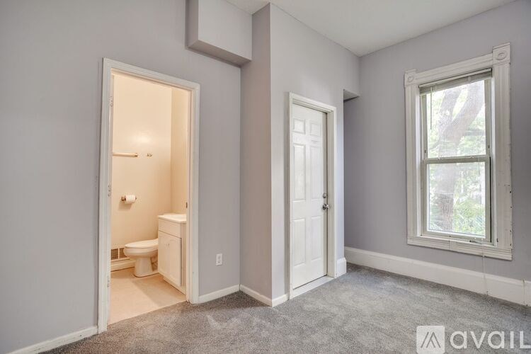 A bathroom with a toilet, sink, and window.