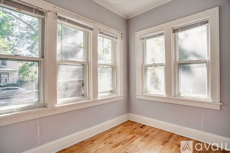 Two windows in a room with wooden floors and white walls.