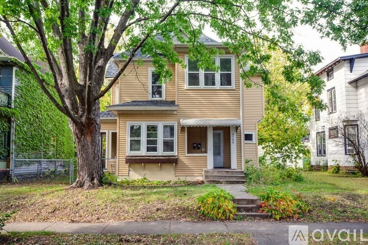 A two-story house with a tree in front.