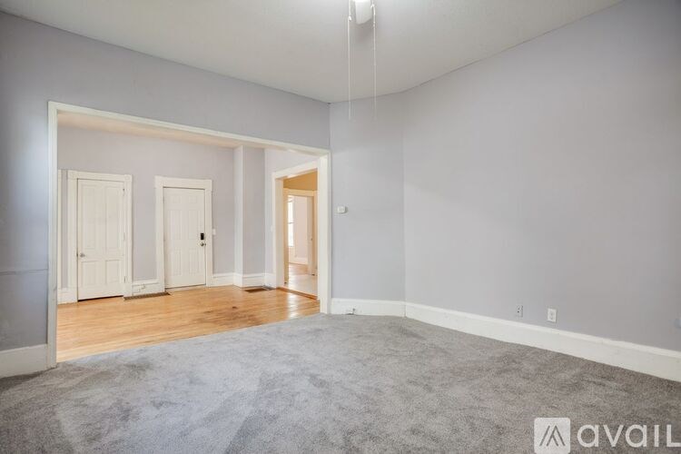 A spacious room with a carpeted floor and white walls.