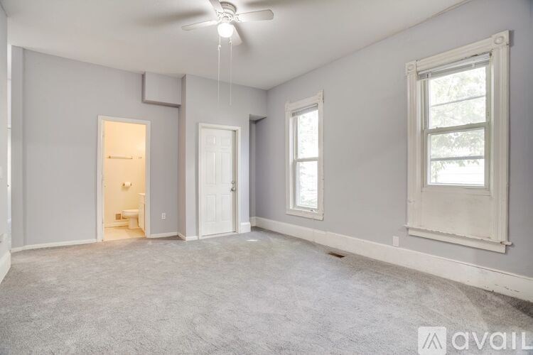 A spacious room with a ceiling fan and three windows.