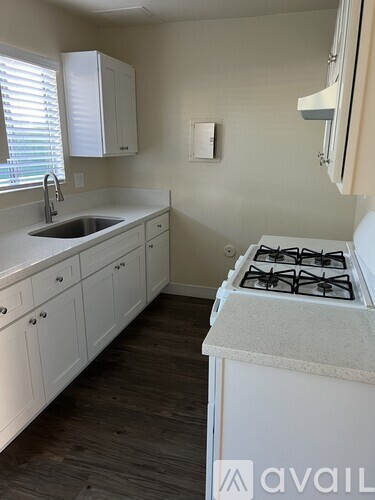 A kitchen with a stove, sink, and cabinets.