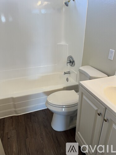 A white toilet sits in a bathroom next to a bathtub and sink.