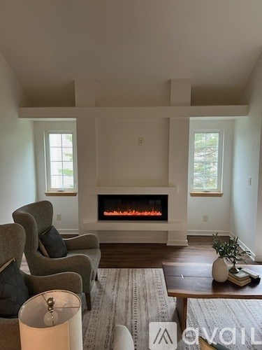 A living room with a fireplace and two chairs.