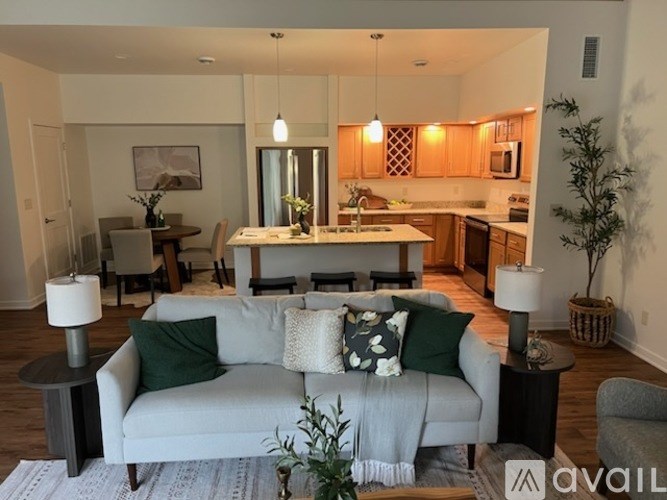 A modern living room with a grey couch and a kitchen in the background.