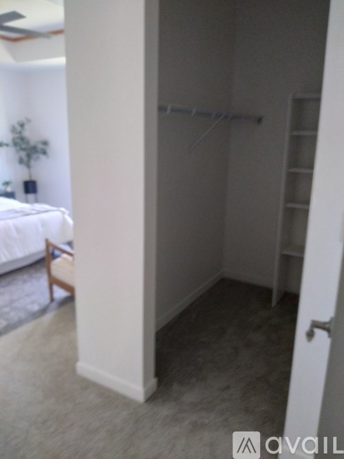 A small room with a white bed and a chair.