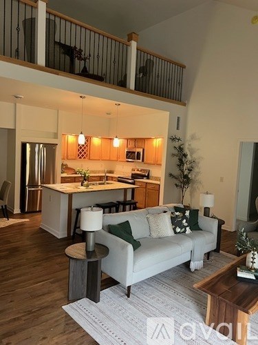 A living room with a couch, a coffee table, and a kitchen in the background.