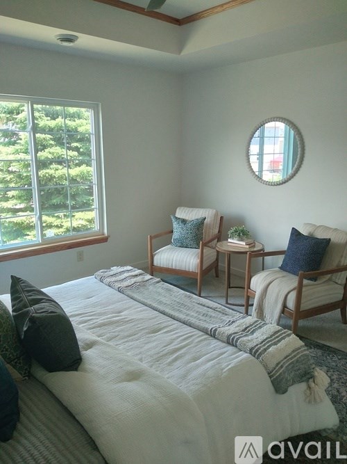A bedroom with a large bed and two chairs.