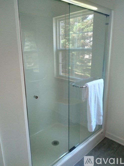 A white towel is hanging on a glass door.