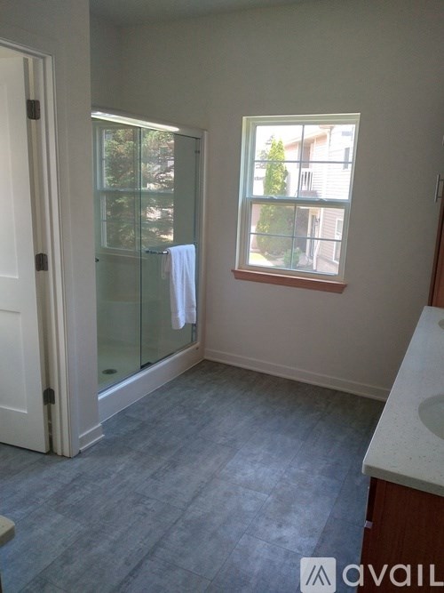 A bathroom with a glass shower door and a window.
