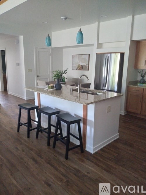 A kitchen with a white island and black stools.
