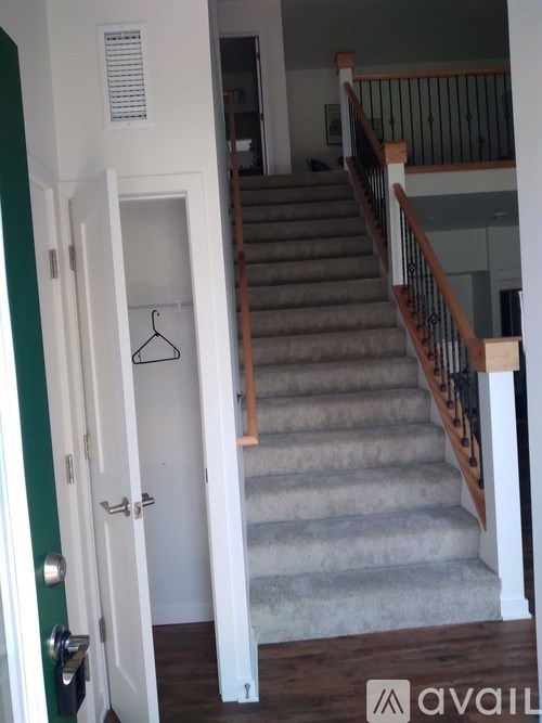 A hallway with a staircase and a door with a hanger on it.