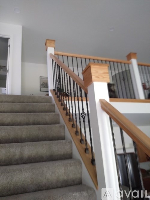 A staircase with a wooden handrail and a grey carpeted runner.