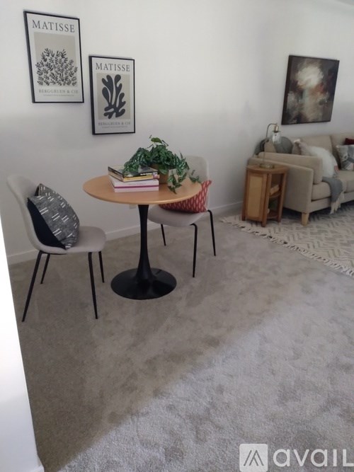 A living room with a round table, a chair, a couch, and a rug.