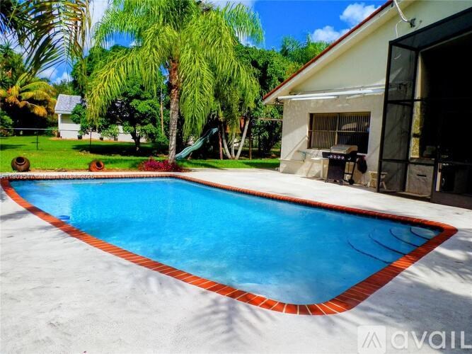 A pool surrounded by a white fence and trees.