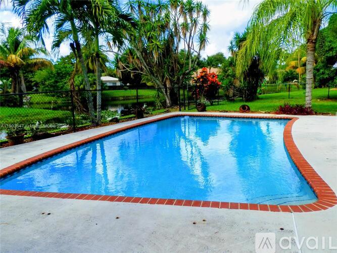 A pool surrounded by trees and a fence.