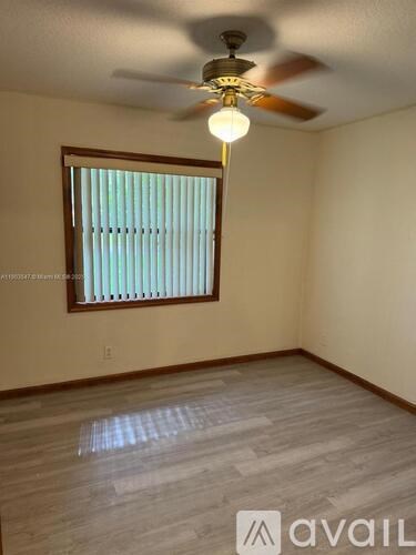 A room with a ceiling fan and a window with blinds.