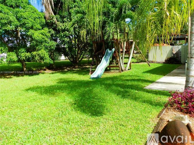 A green slide in a backyard surrounded by trees.