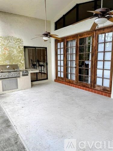 A room with a ceiling fan and a glass door cabinet.