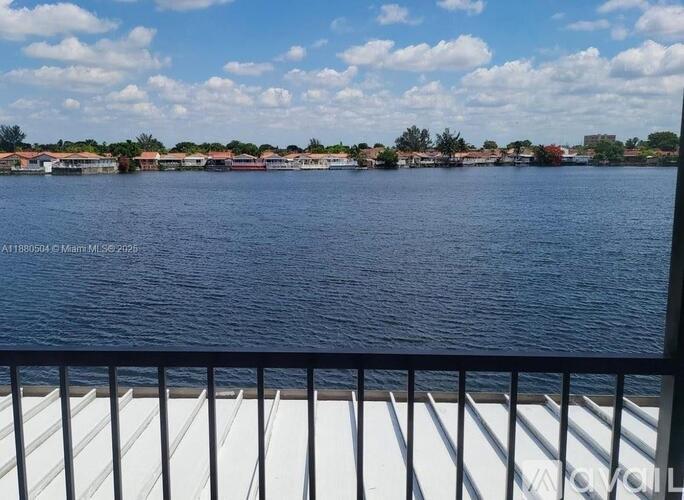 A view from a balcony overlooking a calm body of water with buildings in the distance.