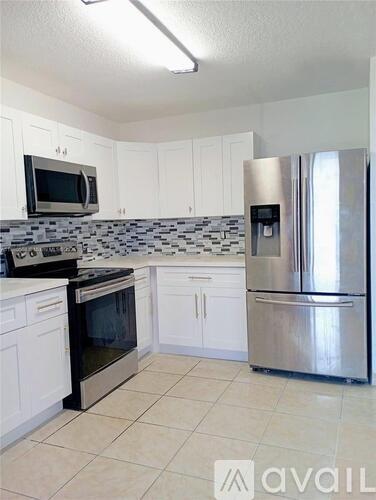 A kitchen with white cabinets and a stainless steel refrigerator.