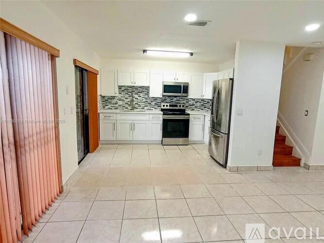 A kitchen with white cabinets and a black and white backsplash.