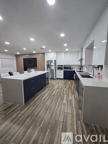 A modern kitchen with a large island and wooden flooring.