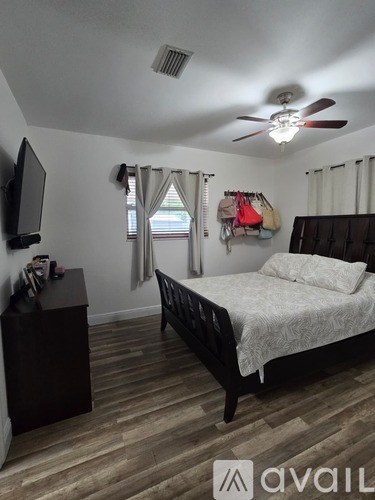 A bedroom with a bed, dresser, and a ceiling fan.